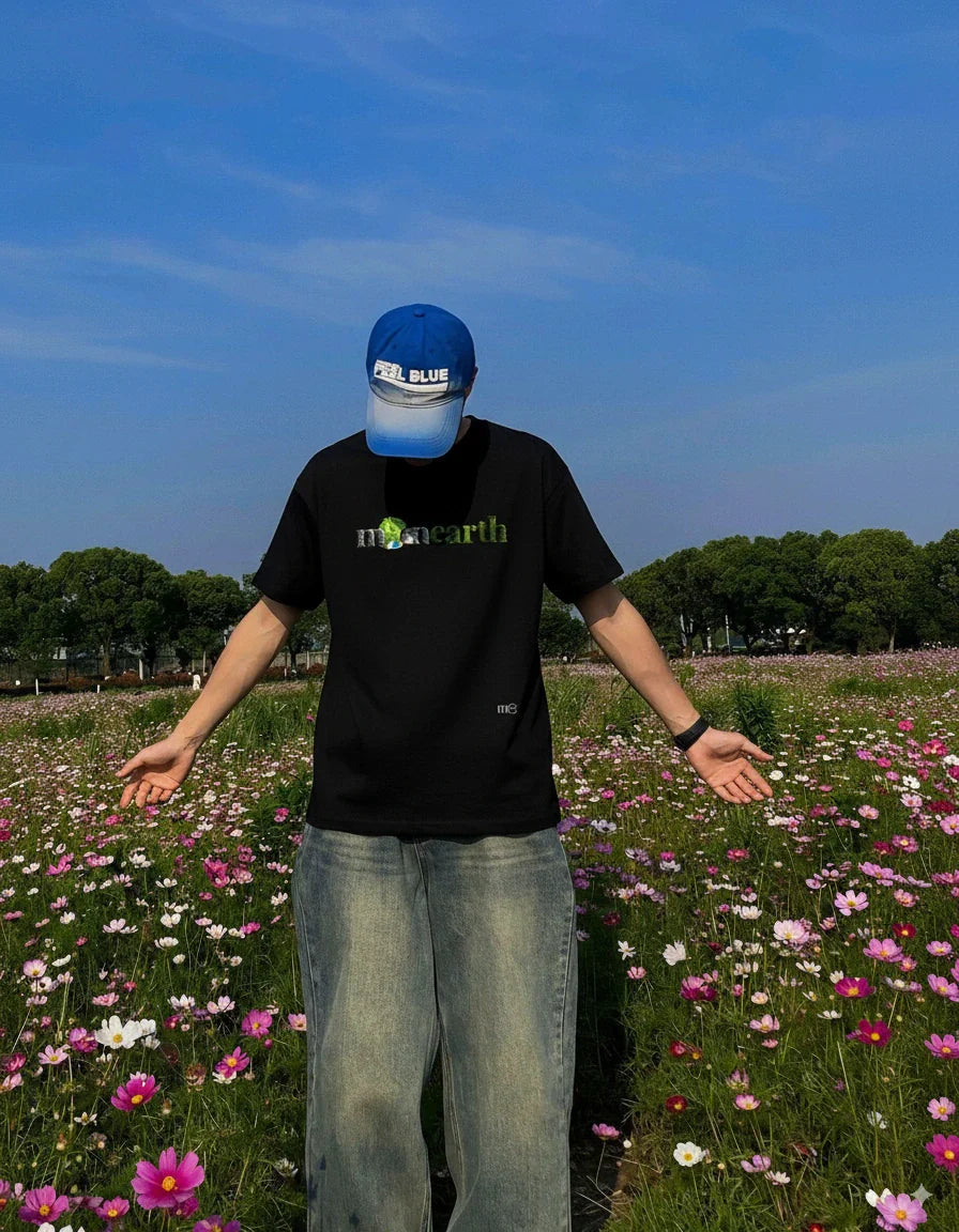 A boy wearing Moonearth T-shirt in a garden with pink flowers
